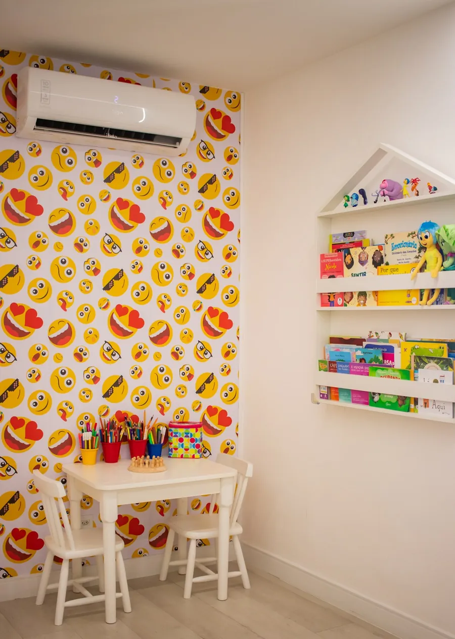 Sala de avaliação com parede de emojis e estante de livros infantis