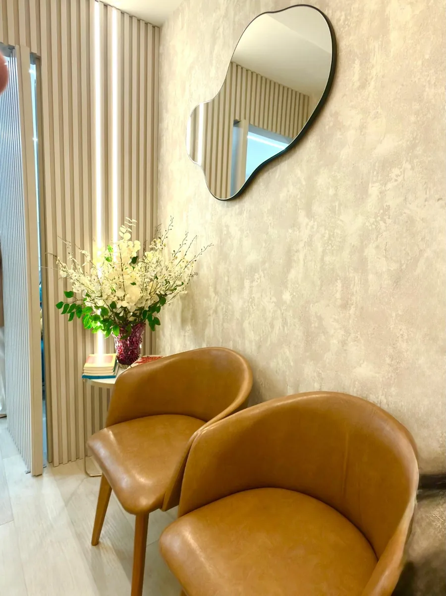 Recepção com poltronas de couro, espelho e flores